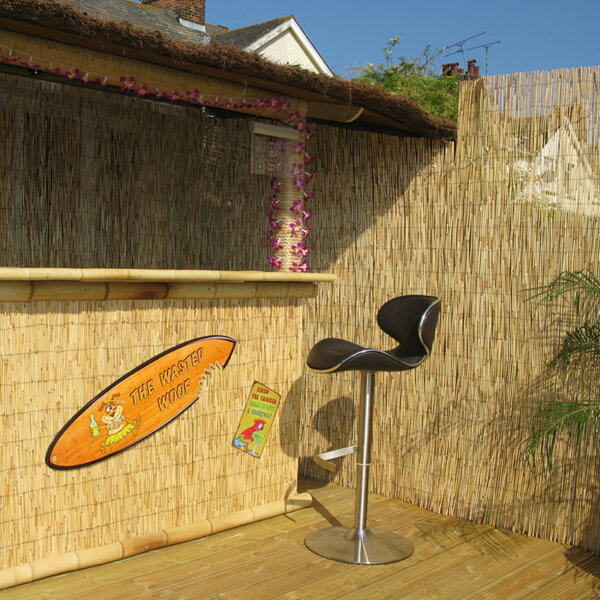 The front of a tiki bar in the summer decorated by bamboo half round poles and bamboo thatch