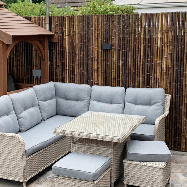 Black bamboo roll screens installed in a customer's garden with grey rattan outdoor seats