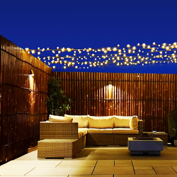 Java black half round bamboo fence panels at night with fairy lights and outdoor lighting