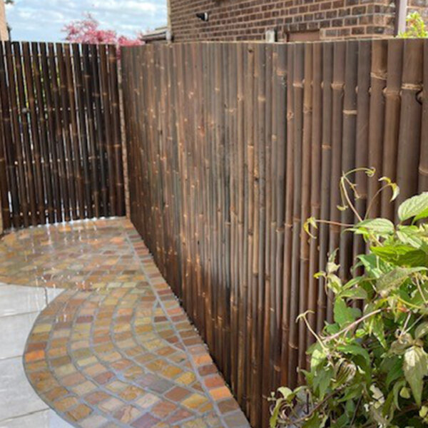 Whole pole Java Black bamboo fence panel in a garden