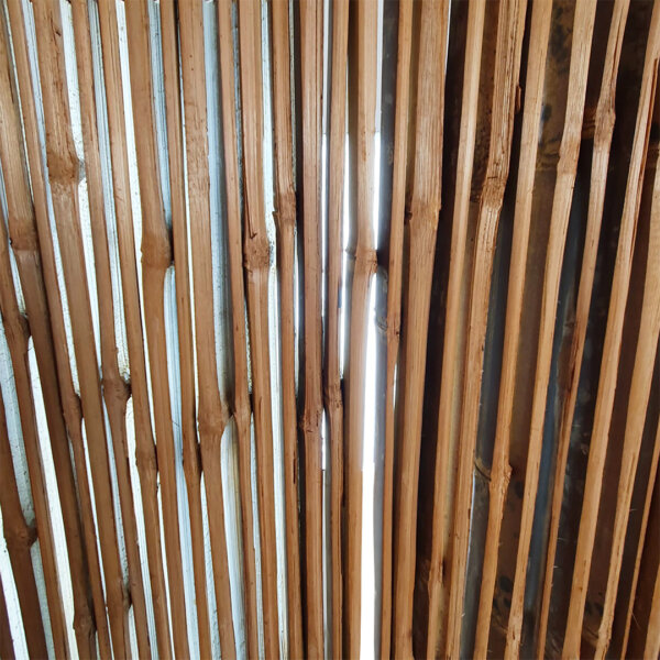 Product image - light shining through the individual slats of the Java Black bamboo side slat fence panel