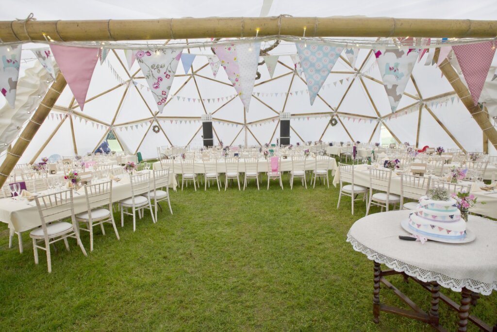 An interior of a geodesic dome made out of bamboo poles with bunting decoration by Atlas Domes