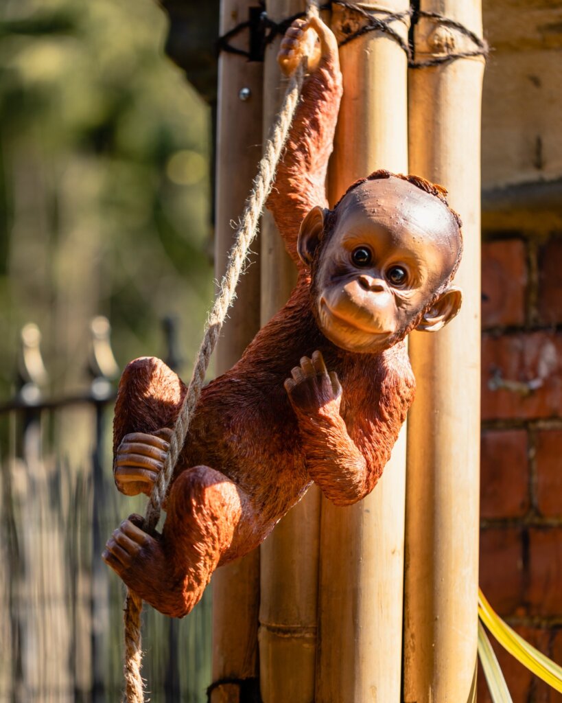 A monkey ornament hands from a rope with a background of bamboo poles at Zen Durham's restaurant